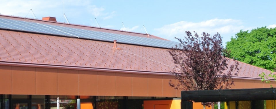 Rote Dachfläche Kindergarten mit oranger Fassade.