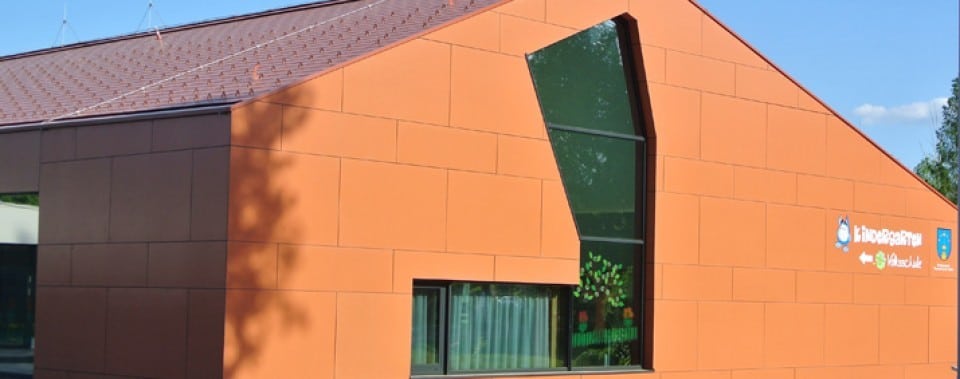 Orange Fassade Kindergarten Frauental mit roter Dachfläche.
